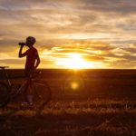 man riding bicycle on green grass field during sunset